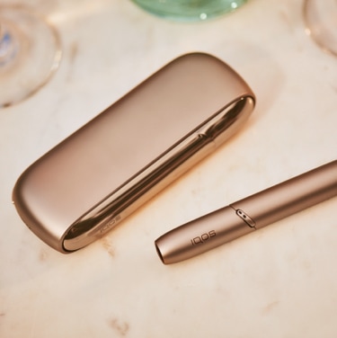 A gold IQOS device and holder.