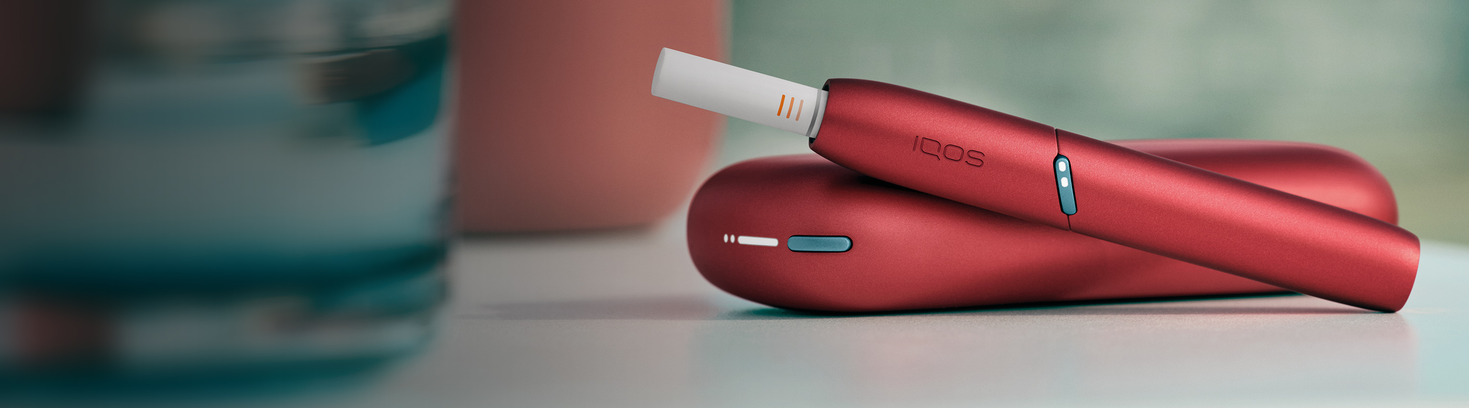 Two people sitting side by side; one holding an IQOS device.