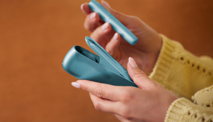 Hands holding IQOS Originals Duo heated tobacco holder and pocket charger in turquoise color. Hands holding IQOS Originals Duo heated tobacco holder and pocket charger in turquoise color.