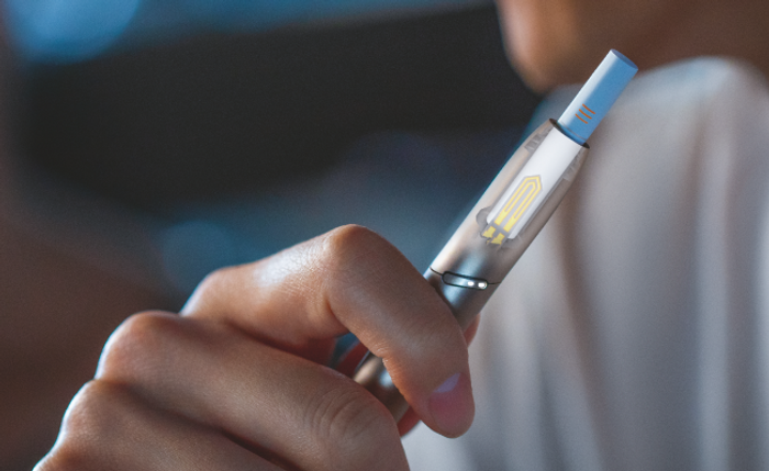 Hand hält einen IQOS DUO Holder , Heizblatt ist sichtbar