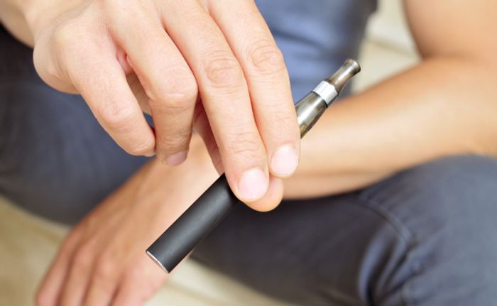 Hand hält schwarze E-Zigarette, Mundstück aus Metal