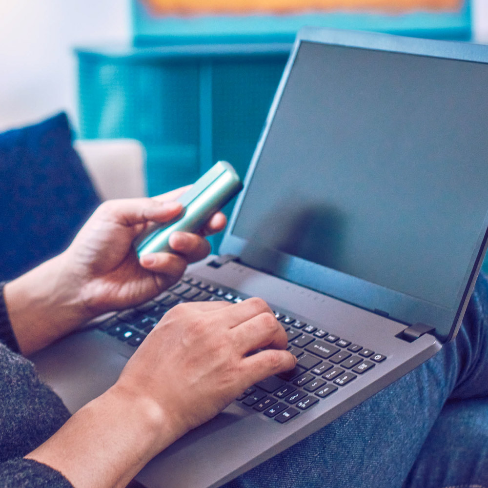 A man searches for FAQs about using the IQOS device on the IQOS website with his laptop.