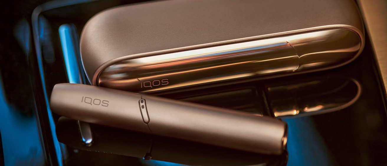 IQOS 3 DUO on a table next to a cup of coffee.